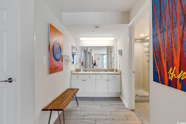 bathroom featuring hardwood / wood-style floors, vanity, a shower with shower door, and a textured ceiling