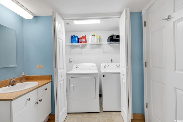 washroom featuring light tile patterned flooring, washer and clothes dryer, and sink