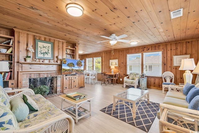 living room featuring a brick fireplace, ceiling fan, wood ceiling, and light wood-type flooring