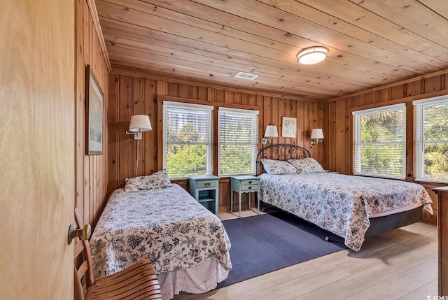 bedroom with light wood-type flooring, wooden walls, and wooden ceiling