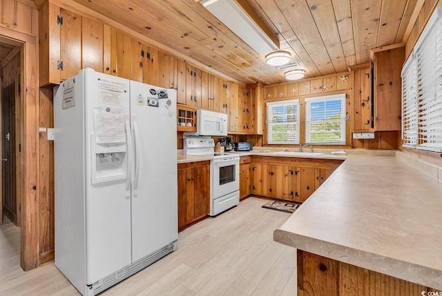 kitchen with wood walls, wooden ceiling, white appliances, light hardwood / wood-style flooring, and sink