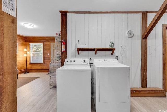 laundry area featuring light hardwood / wood-style floors, independent washer and dryer, and wooden walls