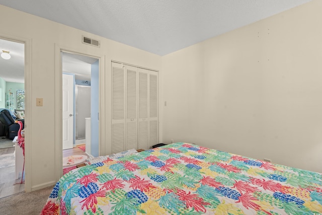 carpeted bedroom with a textured ceiling and a closet