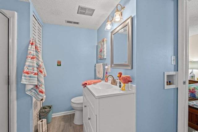 bathroom featuring vanity, wood-type flooring, a textured ceiling, and toilet