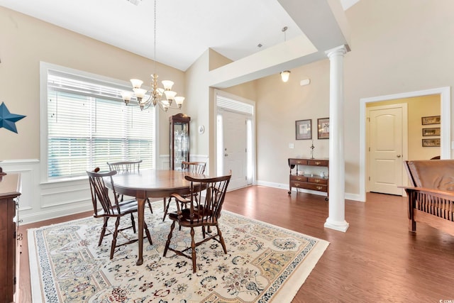 dining space featuring high vaulted ceiling, ornate columns, hardwood / wood-style flooring, and a chandelier