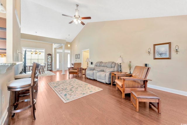 living room featuring high vaulted ceiling, ceiling fan with notable chandelier, and hardwood / wood-style floors