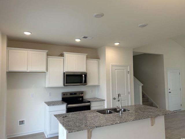 kitchen featuring stainless steel appliances, a kitchen island with sink, sink, and white cabinets