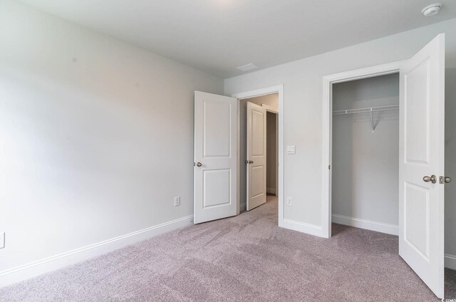 unfurnished bedroom featuring light carpet and a closet