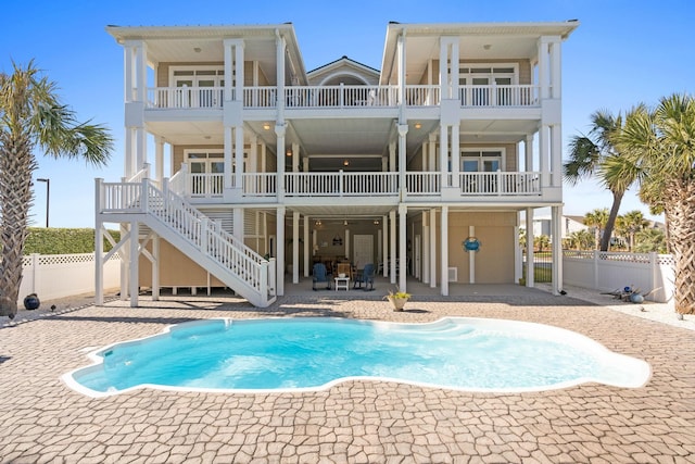 rear view of house with a patio, a fenced in pool, and a balcony