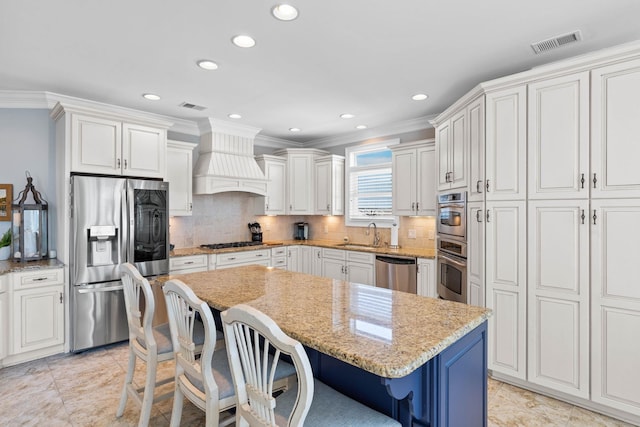 kitchen with light stone counters, stainless steel appliances, custom range hood, tasteful backsplash, and a kitchen island