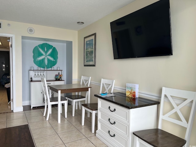 dining area featuring light tile patterned flooring and a textured ceiling