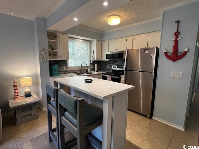 kitchen featuring ornamental molding, sink, backsplash, appliances with stainless steel finishes, and a breakfast bar area