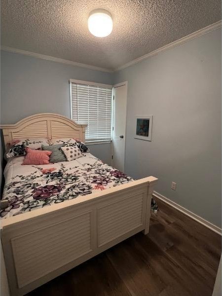 bedroom with a textured ceiling, dark hardwood / wood-style floors, and ornamental molding