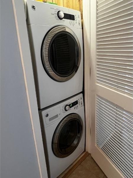 laundry area featuring stacked washer and clothes dryer and tile patterned flooring