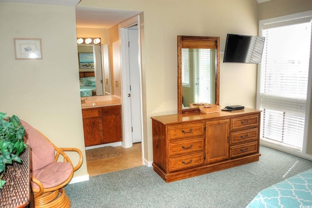 carpeted bedroom featuring sink, connected bathroom, and multiple windows