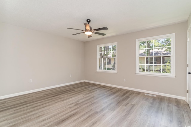 empty room featuring ceiling fan, light wood-type flooring, and a textured ceiling