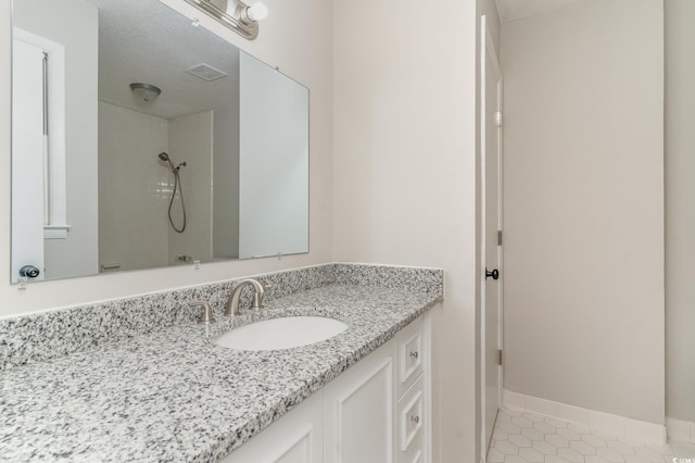 bathroom with a shower, tile patterned flooring, vanity, and a textured ceiling