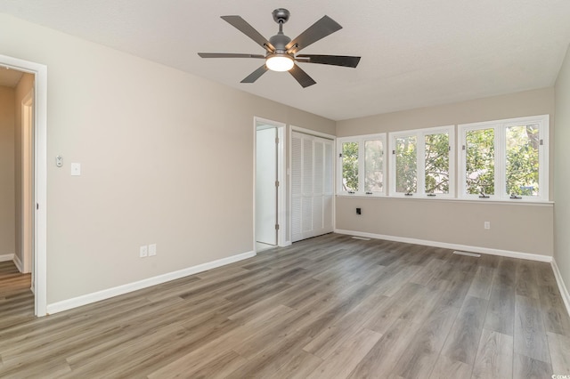 unfurnished bedroom featuring ceiling fan, a closet, a textured ceiling, and light wood-type flooring