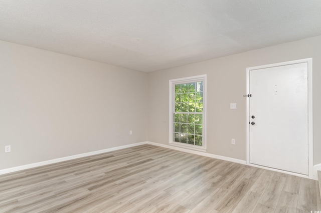 empty room featuring a textured ceiling and light hardwood / wood-style floors