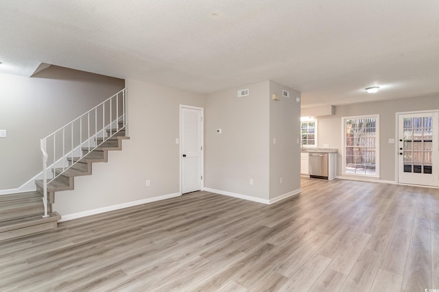 unfurnished living room with light hardwood / wood-style floors and a textured ceiling