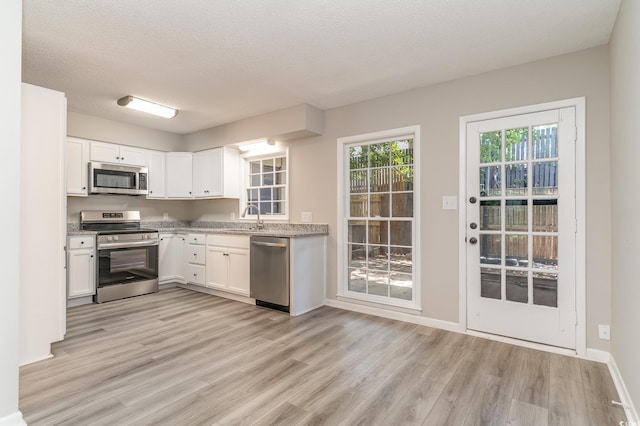 kitchen with white cabinetry, sink, light wood-type flooring, and stainless steel appliances