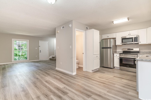 kitchen with appliances with stainless steel finishes, light wood-type flooring, and white cabinetry