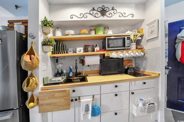 bar featuring stainless steel appliances, decorative backsplash, white cabinetry, and wooden counters