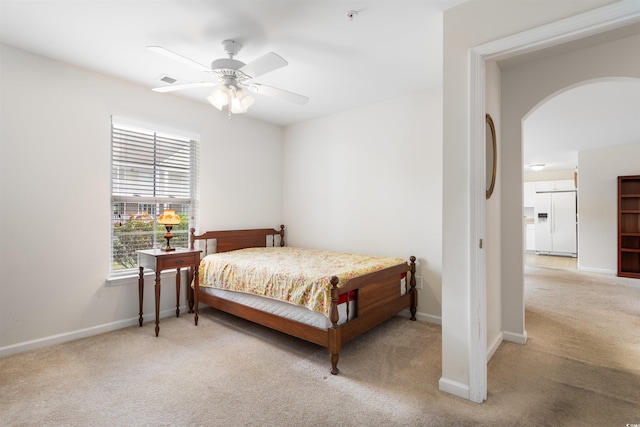 carpeted bedroom featuring white fridge with ice dispenser and ceiling fan