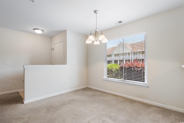 carpeted spare room with a chandelier