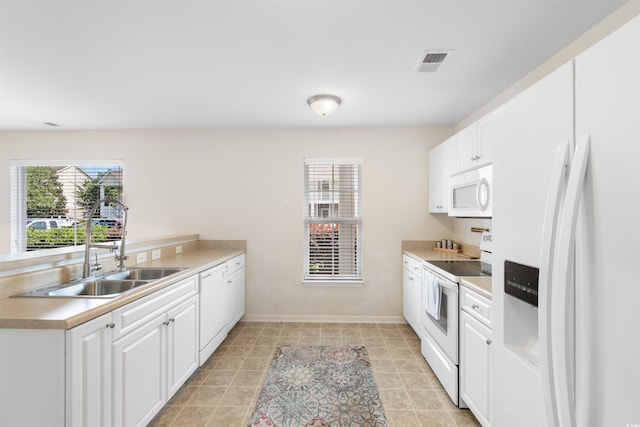 kitchen with white appliances, white cabinetry, and sink