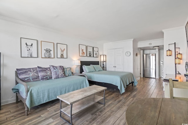 bedroom featuring baseboards, ornamental molding, freestanding refrigerator, and wood tiled floor