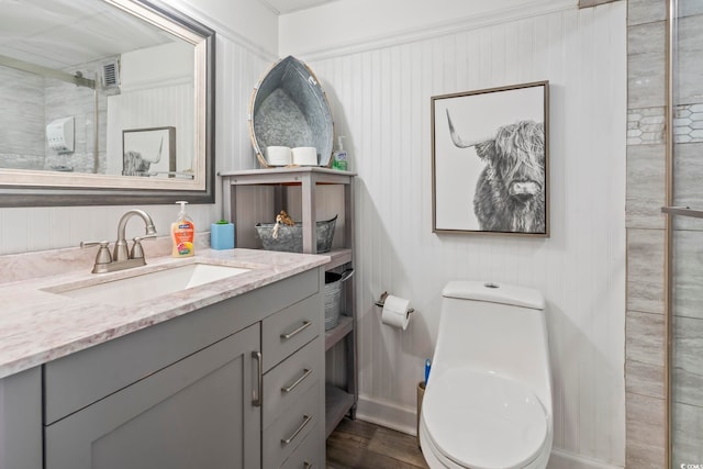 bathroom with tiled shower, vanity, toilet, and wood finished floors