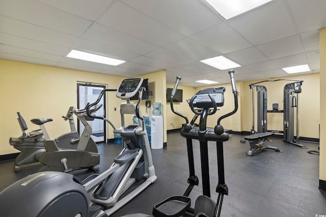 workout area featuring a drop ceiling and baseboards