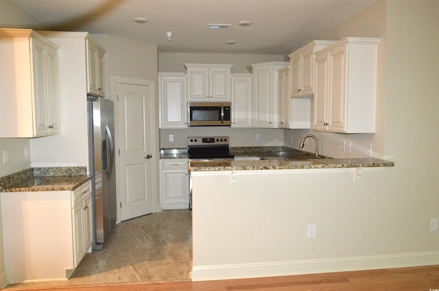 35 Delray Dr Unit 2-C, Murrells Inlet, SC 29576 - kitchen featuring appliances with stainless steel finishes, a peninsula, a kitchen breakfast bar, and dark stone counters
