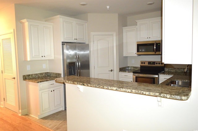 35 Delray Dr Unit 2-C, Murrells Inlet, SC 29576 - kitchen with stainless steel appliances, a peninsula, white cabinetry, and dark stone counters