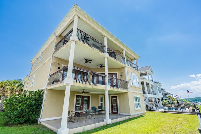 rear view of house featuring a lawn, ceiling fan, a patio area, and a balcony