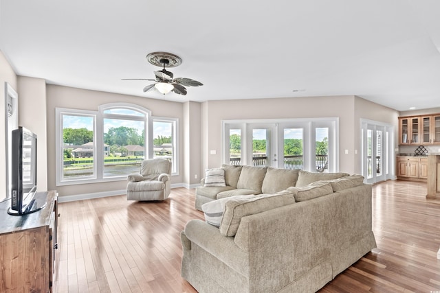 living room with ceiling fan, light hardwood / wood-style flooring, and french doors