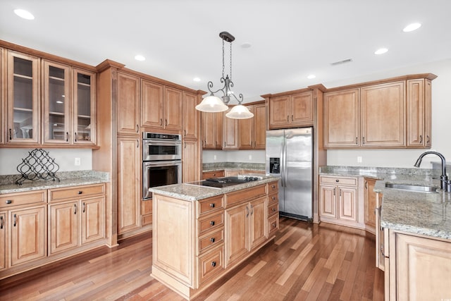 kitchen with pendant lighting, a center island, sink, hardwood / wood-style flooring, and stainless steel appliances