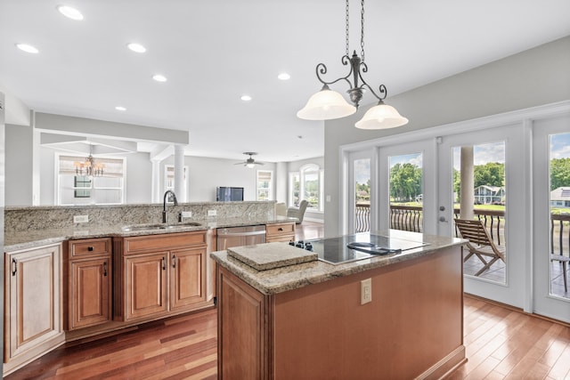 kitchen featuring light stone countertops, stainless steel dishwasher, ceiling fan with notable chandelier, a healthy amount of sunlight, and sink