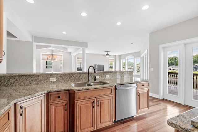 kitchen featuring ceiling fan with notable chandelier, sink, stainless steel dishwasher, light stone countertops, and light hardwood / wood-style floors