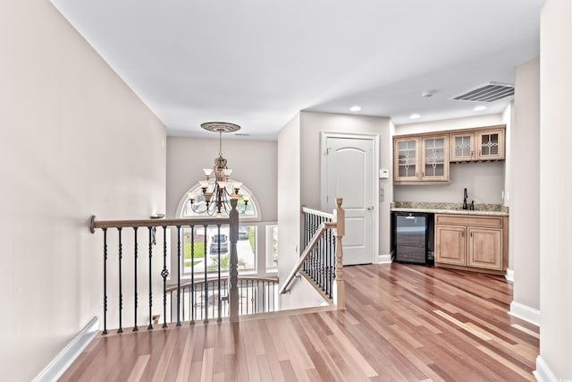 interior space with sink, beverage cooler, light wood-type flooring, and an inviting chandelier