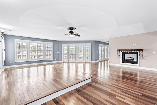 unfurnished living room with a multi sided fireplace, ceiling fan, and hardwood / wood-style floors