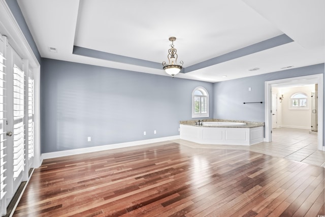 interior space with light hardwood / wood-style floors, a raised ceiling, and a wealth of natural light