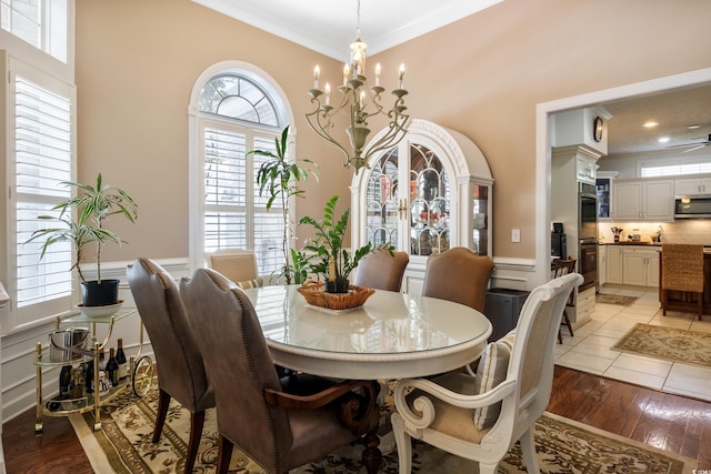 tiled dining room with ornamental molding, a healthy amount of sunlight, and a chandelier