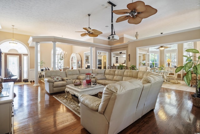 living room featuring plenty of natural light, hardwood / wood-style flooring, ceiling fan, and decorative columns