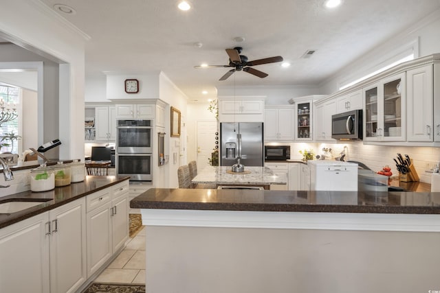 kitchen with ceiling fan, tasteful backsplash, stainless steel appliances, light tile flooring, and ornamental molding