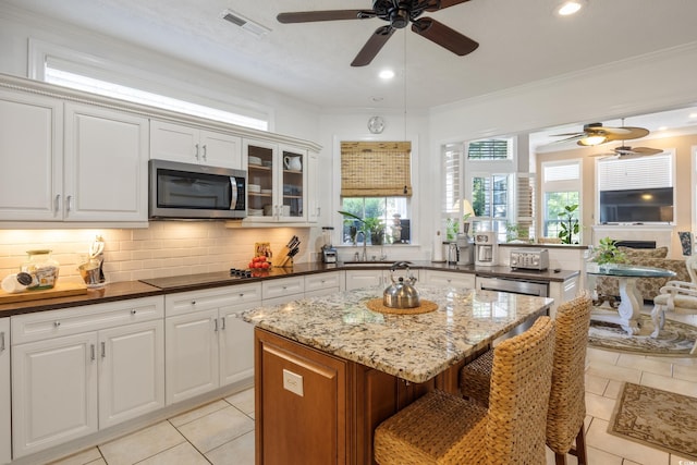 kitchen with ceiling fan, tasteful backsplash, black electric cooktop, and a kitchen island