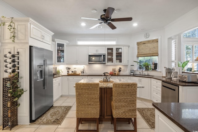 kitchen with appliances with stainless steel finishes, ceiling fan, light tile flooring, and tasteful backsplash