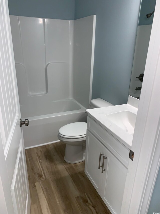 full bathroom featuring wood-type flooring, tub / shower combination, vanity, and toilet