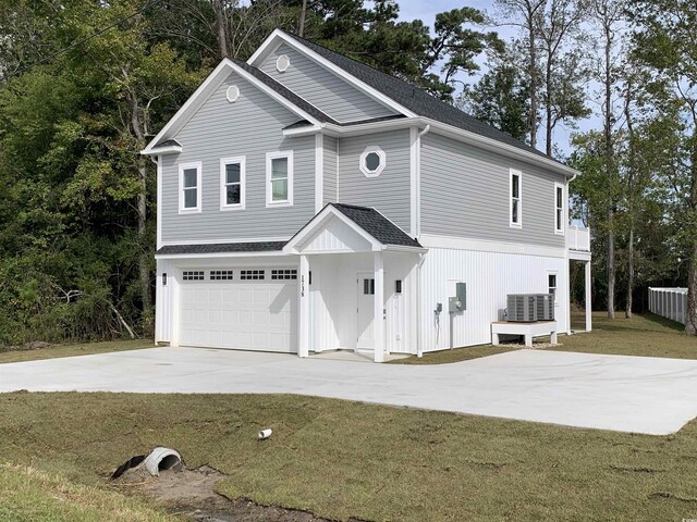 view of front of home with a front yard, a garage, and central AC